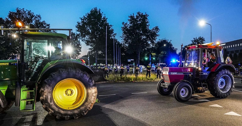 Tractors drive by Dutch police officers standing guard