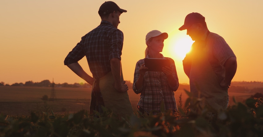 farmers talking in field while sun is setting