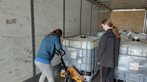 Two women moving chemical tote