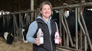 Amy Brickner holding bottles of milk while standing in cattle barn