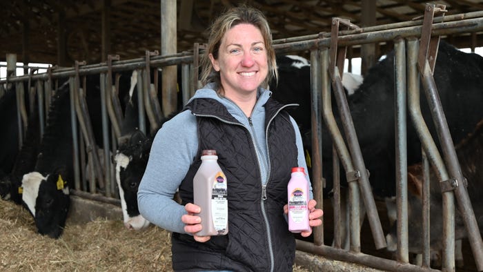Amy Brickner holding bottles of milk while standing in cattle barn Amy Brickner holding bottles of milk while standing in cattle barn