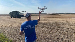 Noah Poynter sending off a drone into flight near a field being harvested