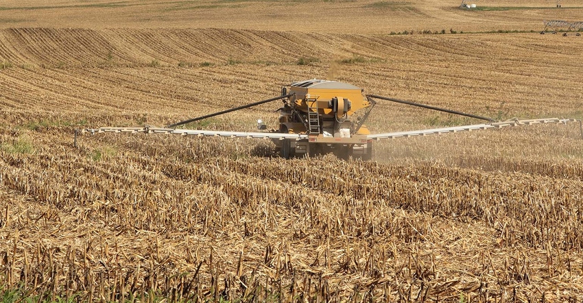 Vehicle spreading fertilizer on a farm field of corn stubble