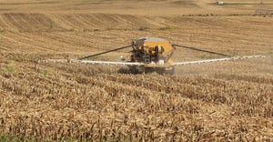 Vehicle spreading fertilizer on a farm field of corn stubble