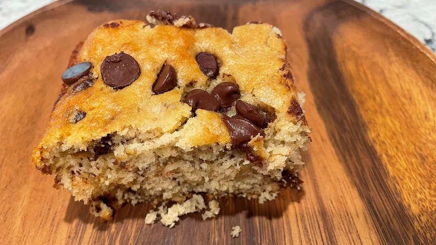 A slice of banana chocolate chip cake on a wooden surface