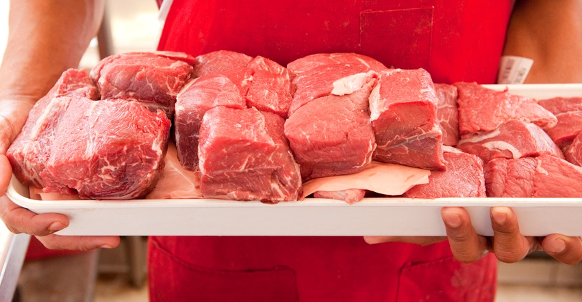 Butcher holding fresh cut meat on tray