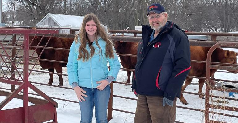 Kali Nickell stands with Garth Griffin in front of the group of Red Angus heifers