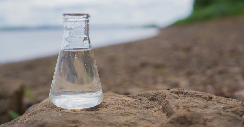 glass flask positioned on rocks in front of the ocean