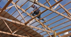 a construction worker secures rafters on a dairy barn