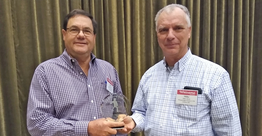 Ken Horton holds the 2020 Premier Seed Grower award presented to him by Kansas Crop Improvement Association president Mike Si