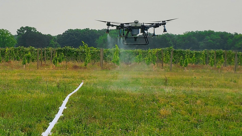A drone flying over and spraying a field
