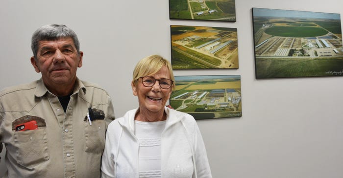 Tom and Judy McCarty standing infront of an aeriel image of the families dairy farms