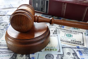 Wooden gavel next to book on pile of money