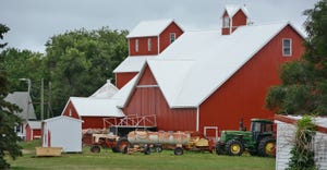 scenic red barn with tractors and tank in barnyard