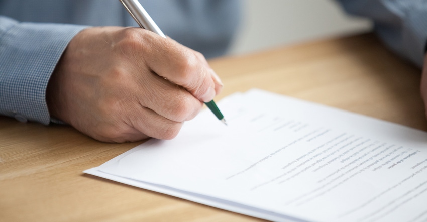 hand holding pen to sign paper