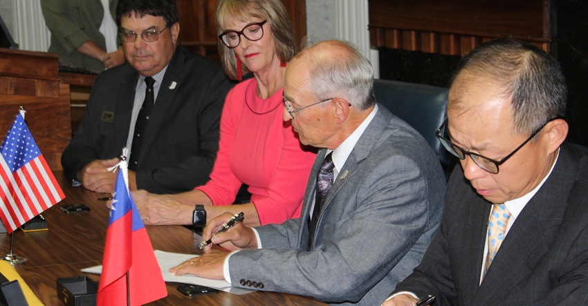David Rodibaugh and Ching-Chao Chan sign trade agreement while Suzanne Crouch and Phil Ramsey watch