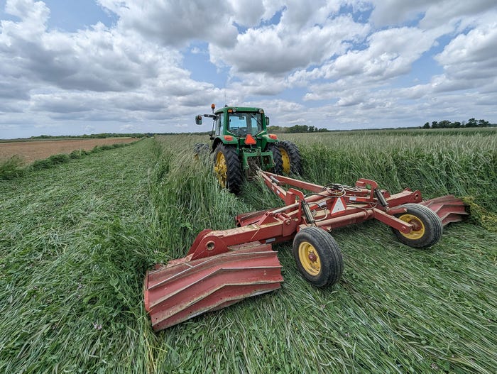 A 20-foot folding-wing roller crimper driving over crops