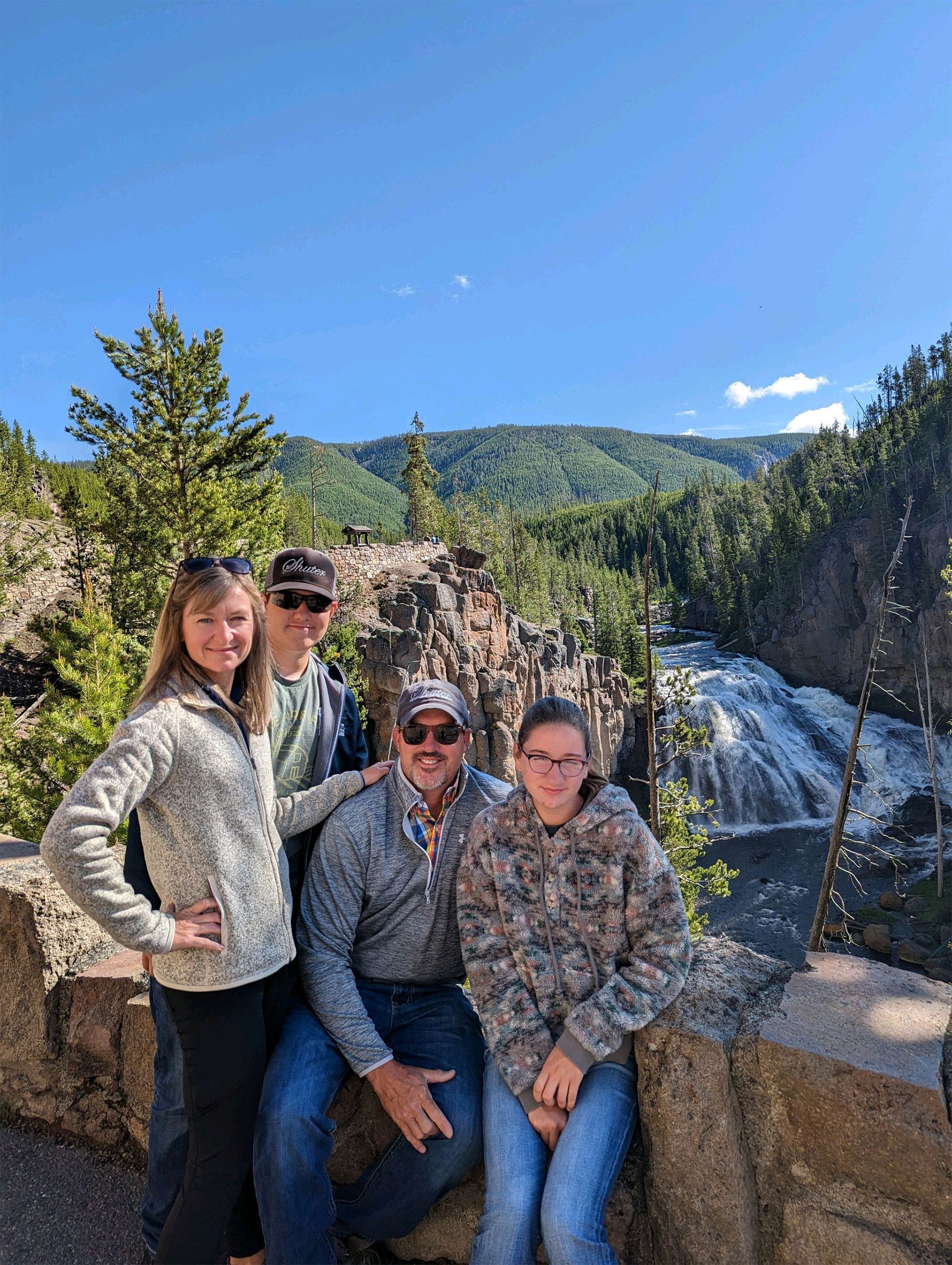 Sarah, Jacob, Brian and Carly Shuter pose in front of a river and small mountains covered with trees