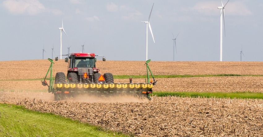 Tractor and planter in field with windmills
