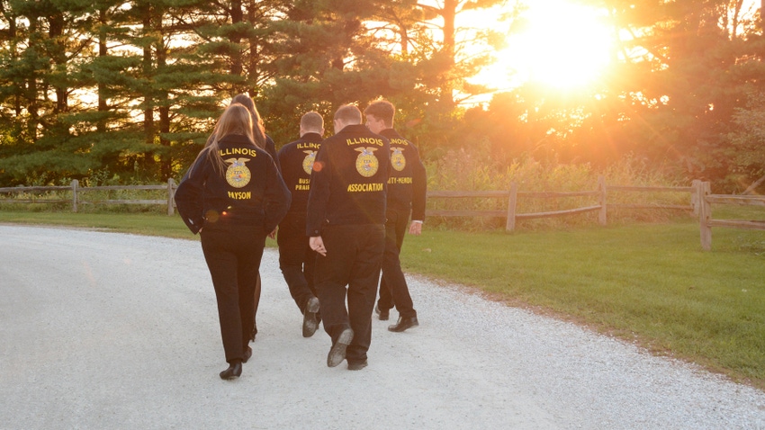 FFA members in their FFA official dress walking down gravel path at sunset