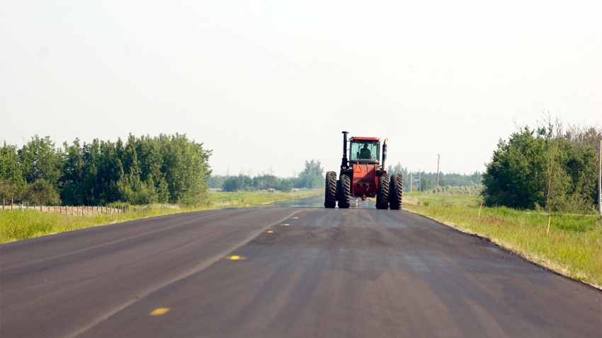 A large tractor driving down a rural road