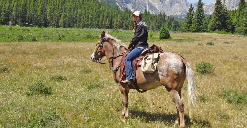 Megan Nelson on her horse with mountains in the background