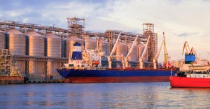 Bulk carrier ship in river port. Dry cargo grain elevator trade. Agrarian maritime facility. Cargo ship in the sea. Sunset vi