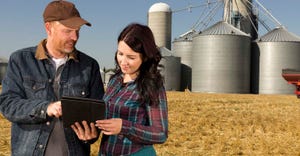 Father and daughter talking in field looking at computer