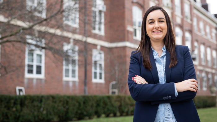 Joana Colussi in a blue blazer, standing with arms crossed