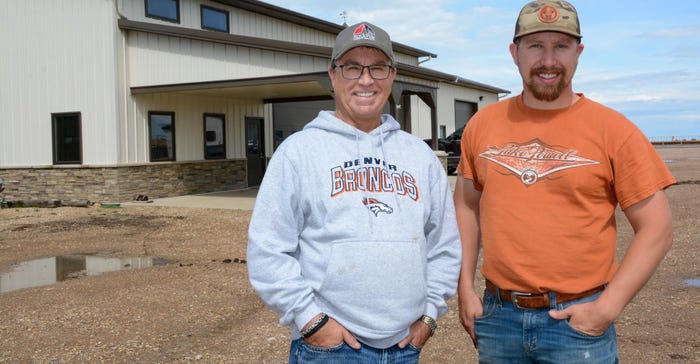 Curt and Marcus Dacar posing for a photo in front of a building