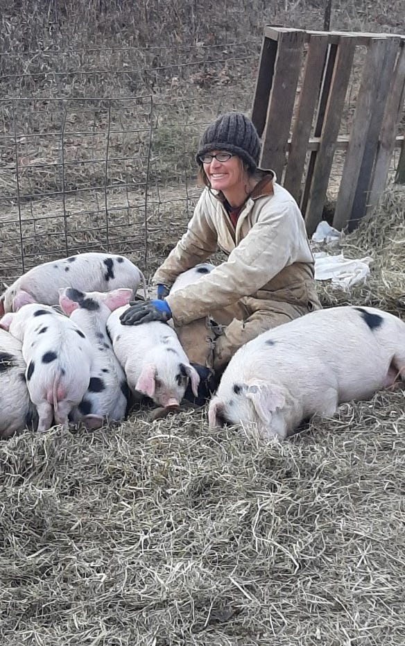 April Prusia kneels, surrounded by heritage pigs 