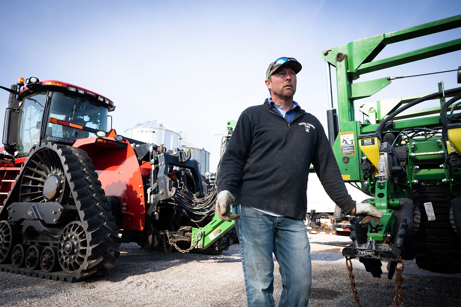 a farmer standing in front of machinery a farmer standing in front of machinery