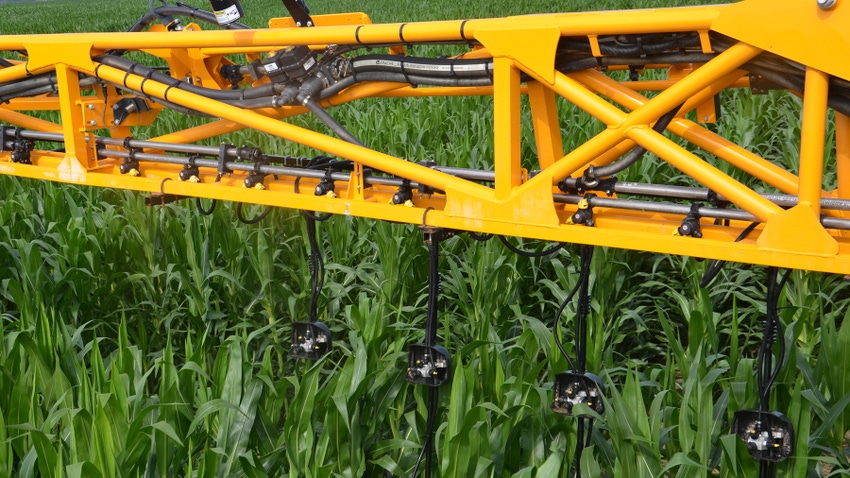 closeup of yellow boom applying liquid N to cornfield midseason