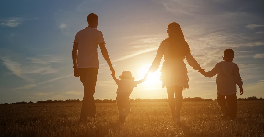 Family with children walking in field with sunsetting