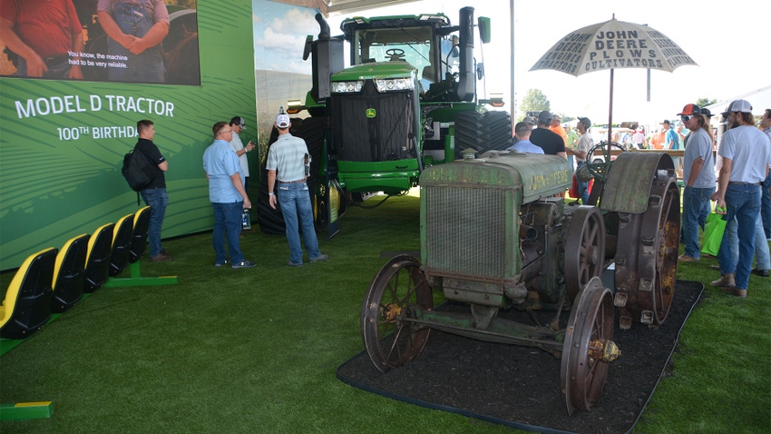 A John Deere Model D tractor and a 9R 640 tractor on display at an exhibition
