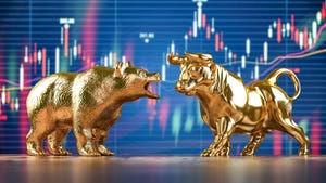 Gold bull and bear figurines in front of market chart