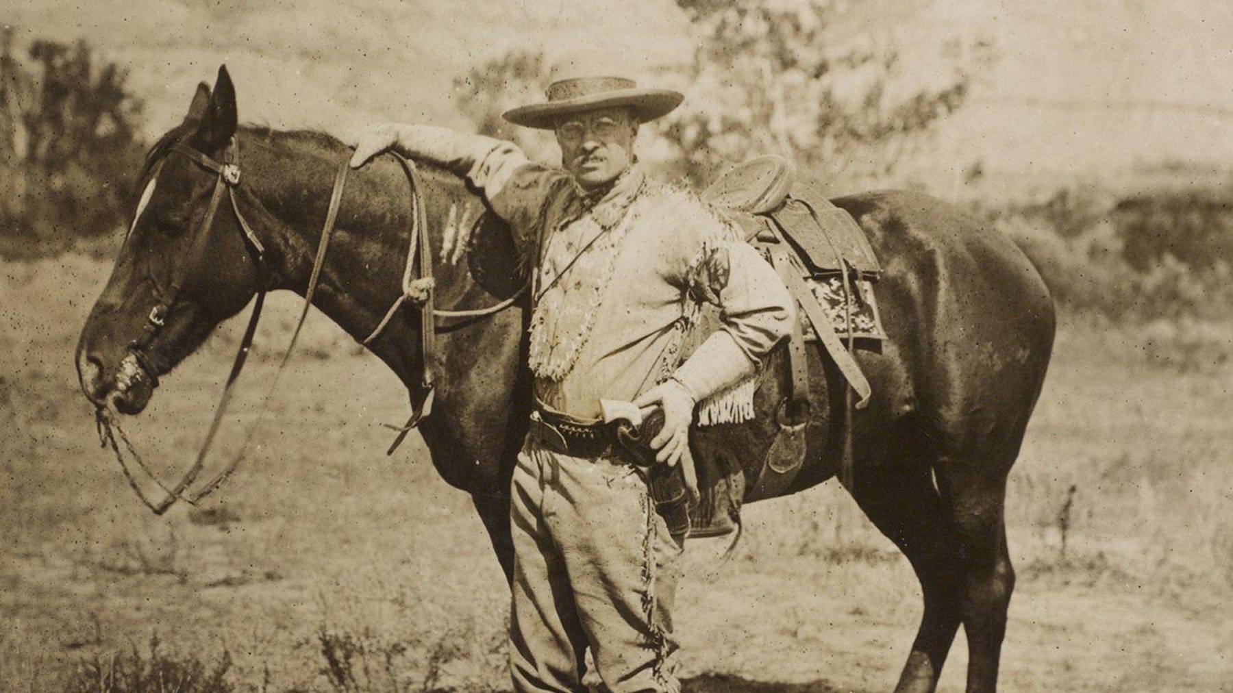 Theordore Roosevelt stands next to his horse