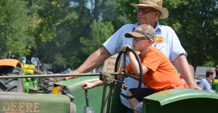 older man teaching young boy to drive tractor