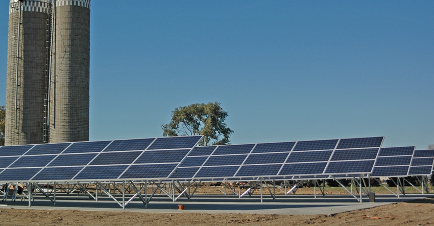 Solar panels on farm with silos in background