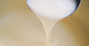 dairy cream being poured out of metal spoon
