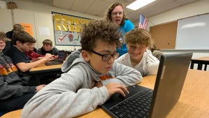 Kids and adult at computer in classroom