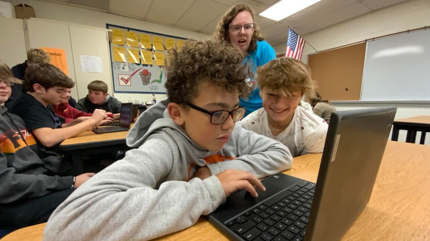 Kids and adult at computer in classroom