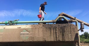 Mike Hunter readies to dump a cup of biocontrol nematodes into a manure tanker
