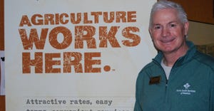 Doug Burns standing infront of Agriculture works here sign