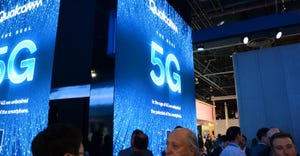 Trade show attendees walk near booth graphics advertising 5G internet