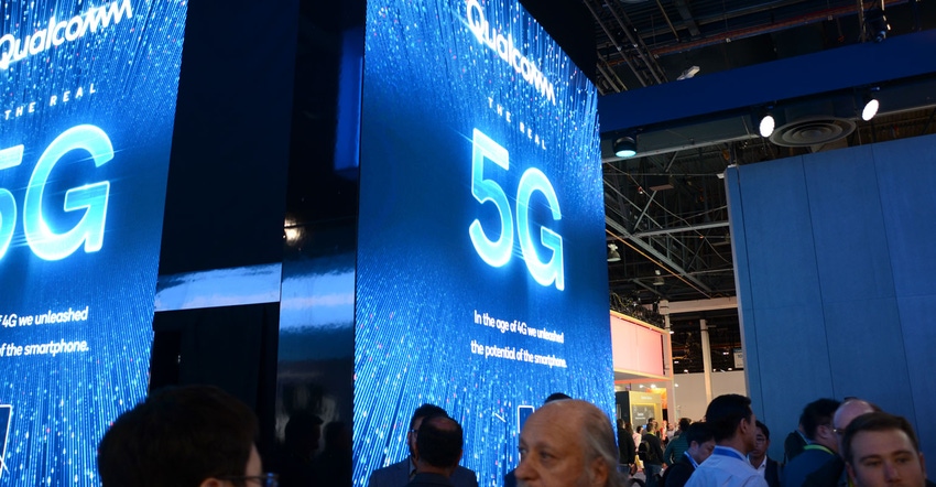 Trade show attendees walk near booth graphics advertising 5G internet Trade show attendees walk near booth graphics advertising 5G internet