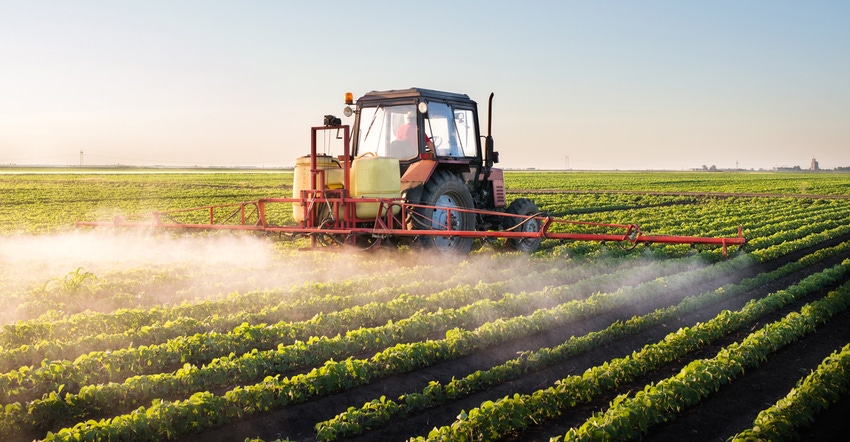 A tractor spraying a soybean field