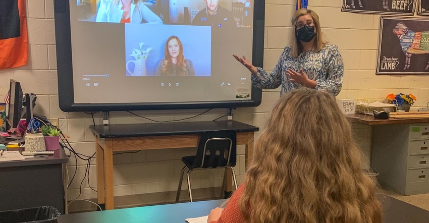 A teacher wearing a face mask and showing a Farm Progress Virtual Experience session with students in a classroom