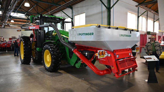 A John Deere 8R tractor with a Pottinger front hopper and Terradisc disk harrow