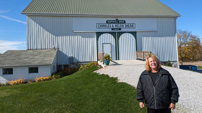 Deb Conner standing in front of a restored white barn